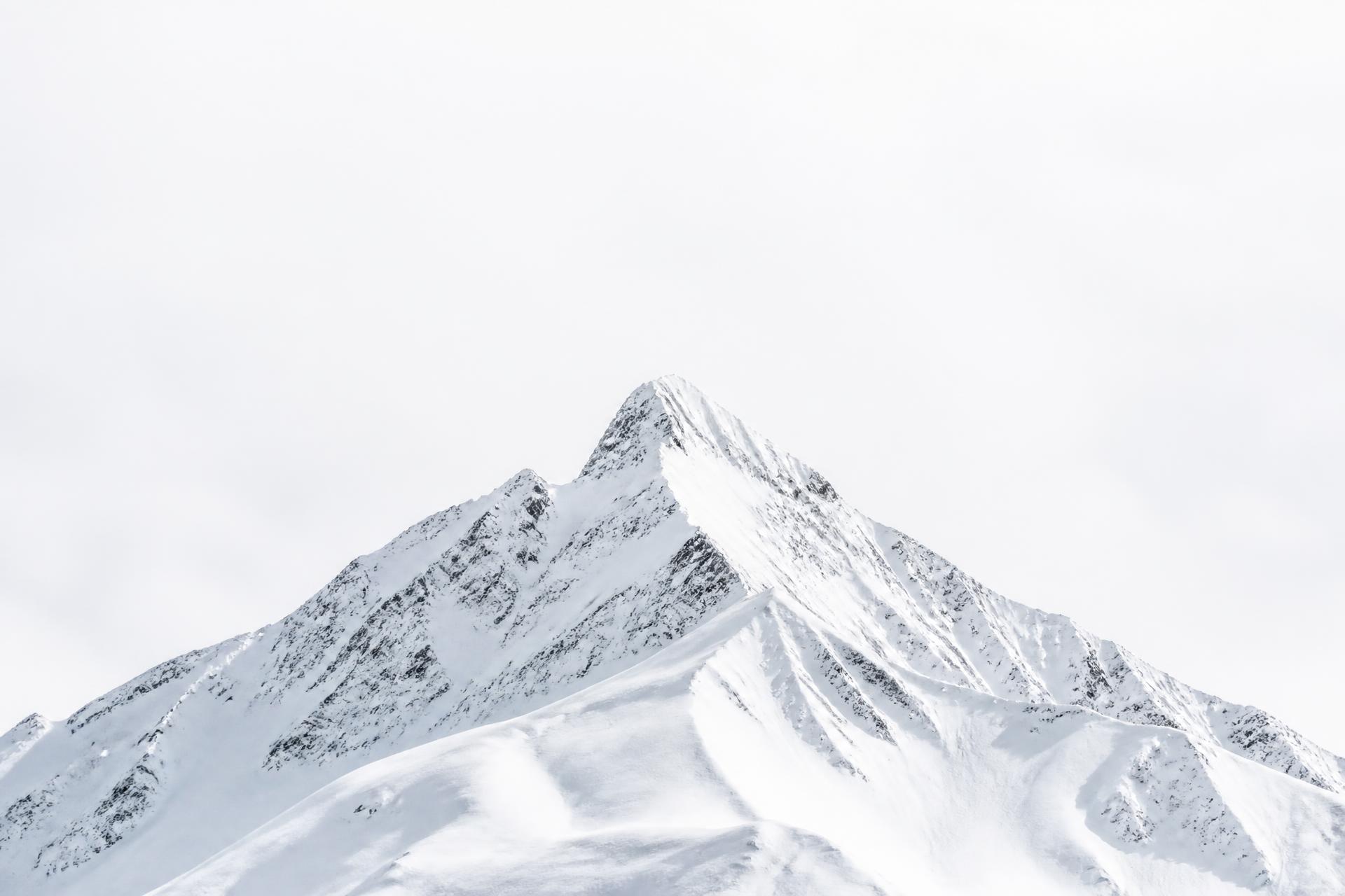 Snow-covered mountain peak under a bright white sky
